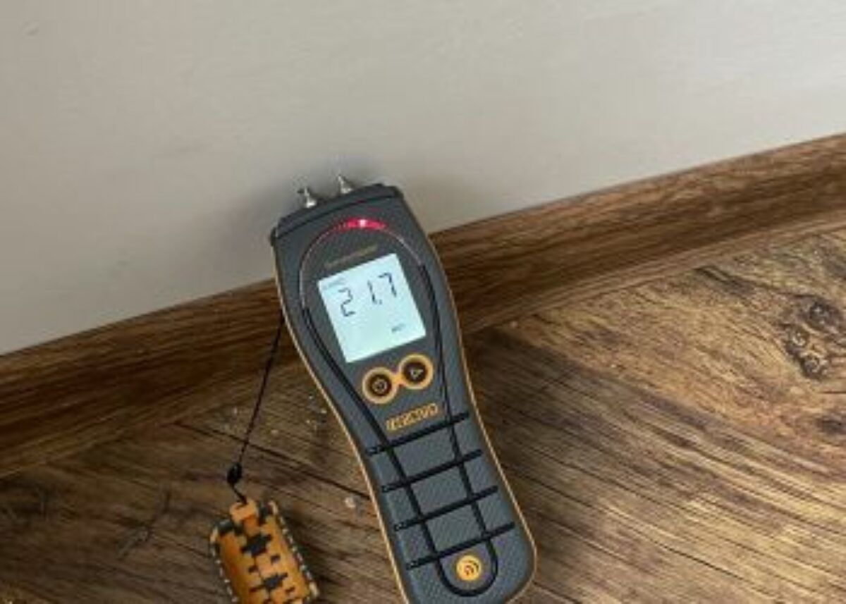 Surveyor using damp meter on a cracked brick wall in a Surrey property, identifying moisture levels